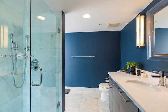 bathroom featuring tile patterned flooring, vanity, a shower with shower door, and toilet