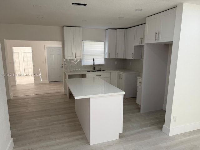 kitchen featuring white cabinets, sink, light hardwood / wood-style floors, and a kitchen island