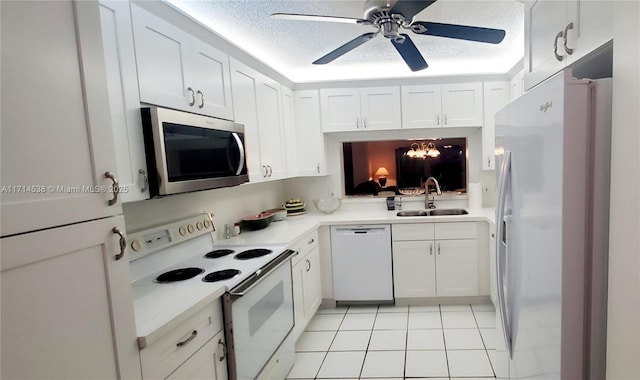 kitchen with sink, white appliances, light tile patterned flooring, a textured ceiling, and white cabinets