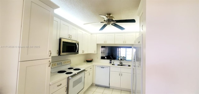 kitchen featuring light countertops, white cabinets, a sink, a textured ceiling, and white appliances