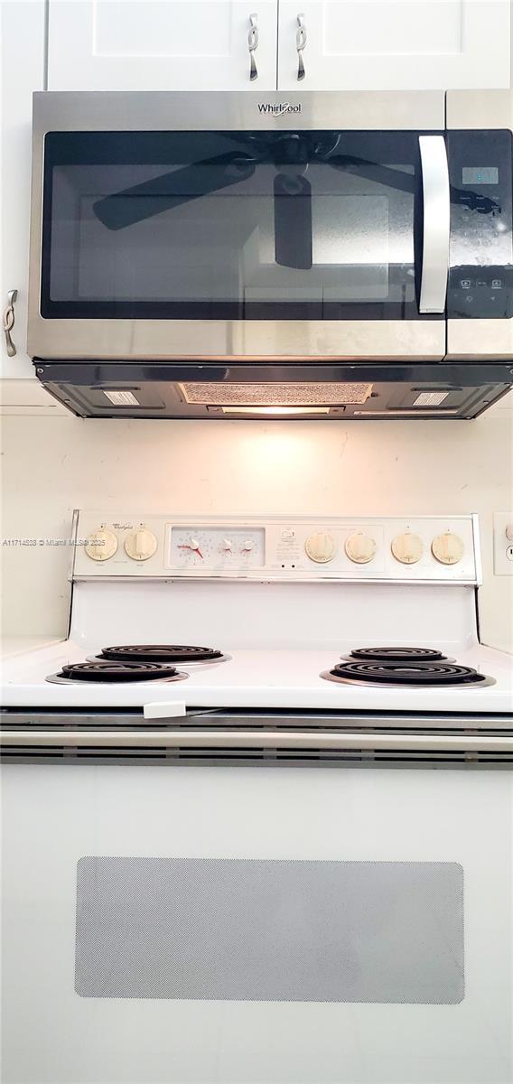 room details featuring light countertops, stainless steel microwave, and white cabinets