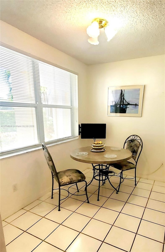 dining space with a textured ceiling and light tile patterned floors