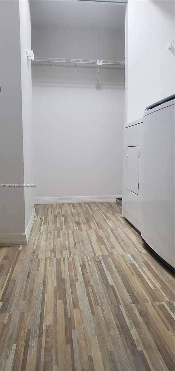 spacious closet featuring light wood finished floors and washing machine and clothes dryer