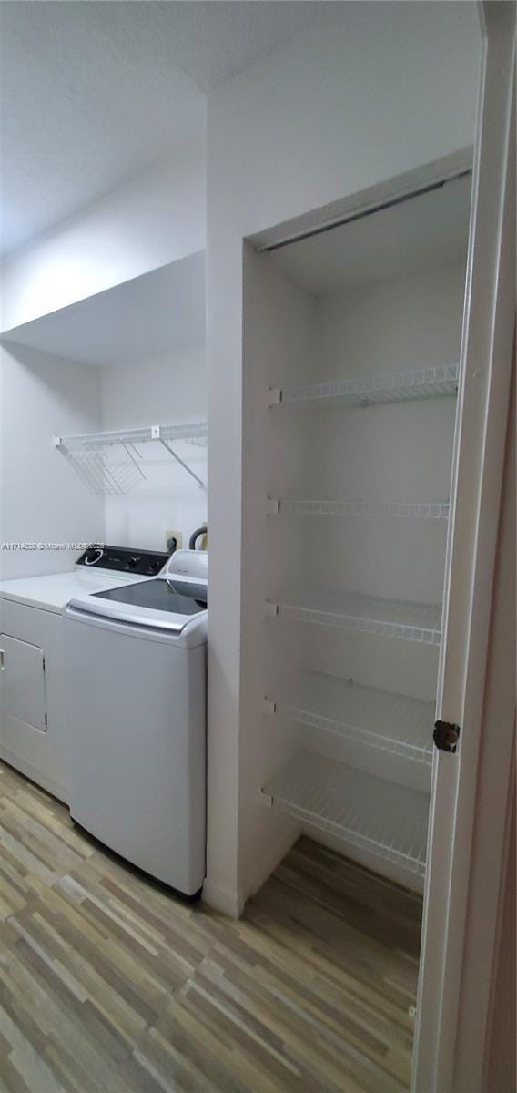 clothes washing area with laundry area, light wood finished floors, and washing machine and clothes dryer