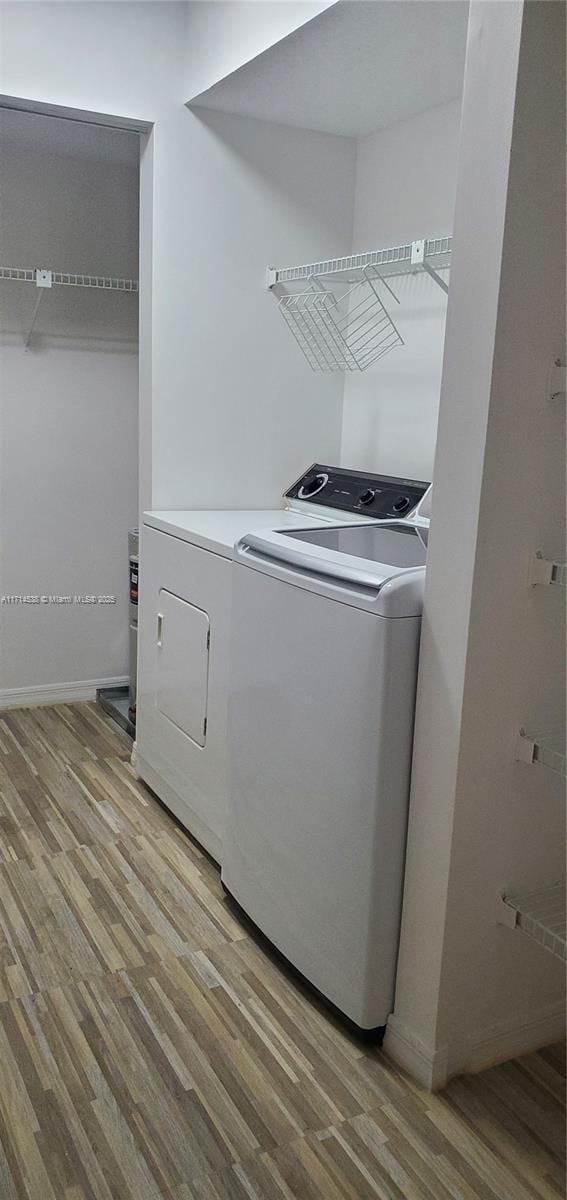 clothes washing area with light wood-style floors, laundry area, and washing machine and clothes dryer