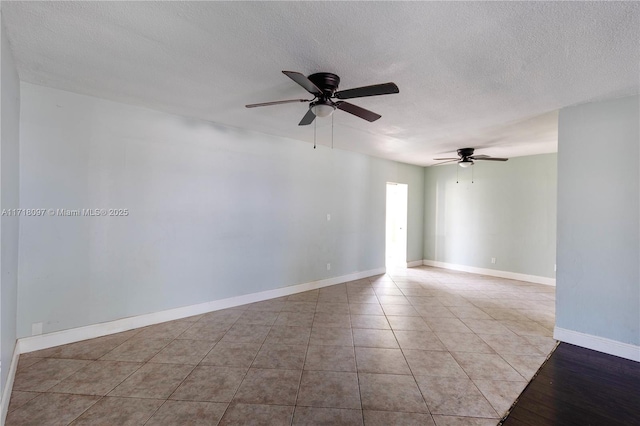 unfurnished room with ceiling fan, light tile patterned floors, and a textured ceiling