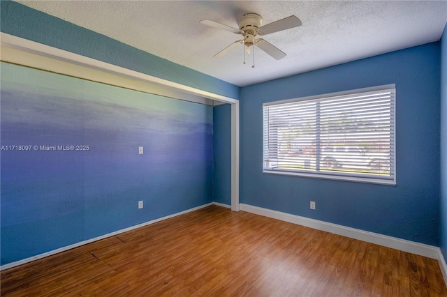 empty room featuring ceiling fan, wood-type flooring, and a textured ceiling