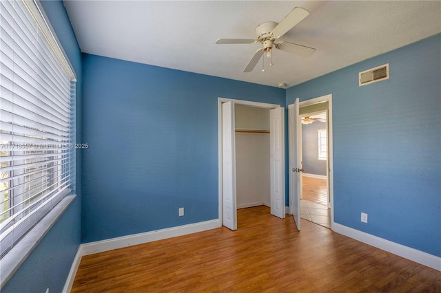 unfurnished bedroom featuring ceiling fan, wood-type flooring, and a closet