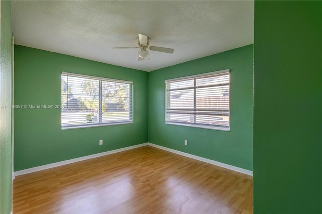 empty room featuring a textured ceiling, light hardwood / wood-style floors, and ceiling fan