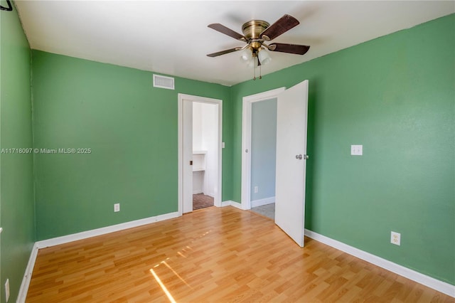 unfurnished bedroom with a spacious closet, ceiling fan, and wood-type flooring