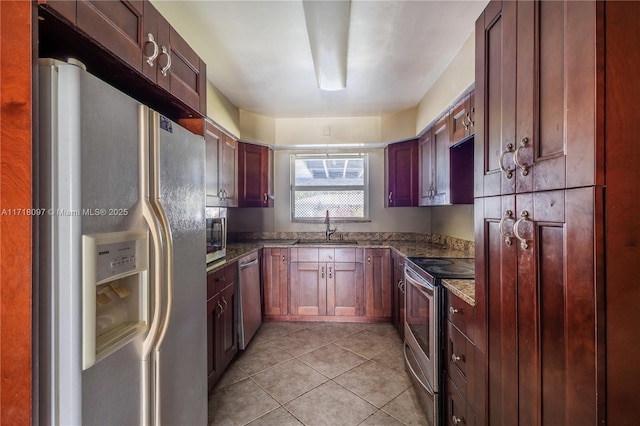 kitchen featuring appliances with stainless steel finishes, light tile patterned floors, dark stone counters, and sink