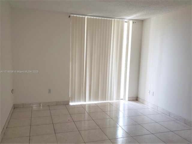 spare room featuring light tile patterned floors and a textured ceiling