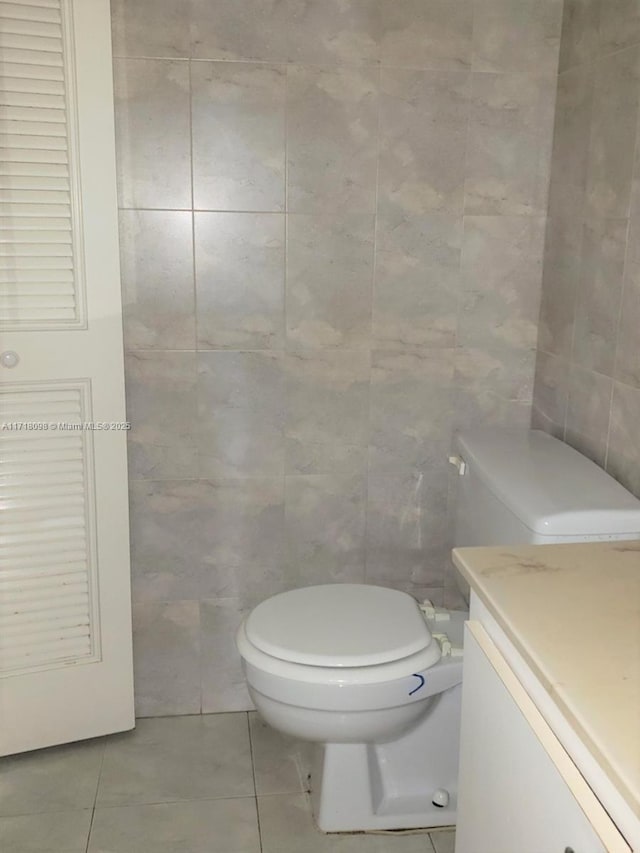 bathroom with tile patterned flooring, vanity, toilet, and tile walls