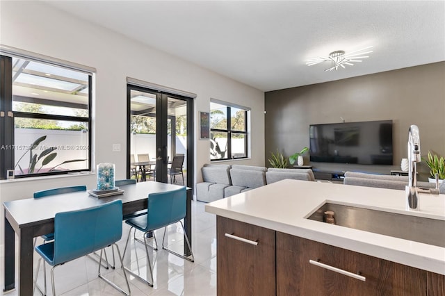 kitchen featuring light tile patterned flooring, a textured ceiling, dark brown cabinetry, and sink