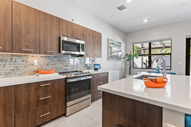 kitchen featuring appliances with stainless steel finishes, tasteful backsplash, a textured ceiling, sink, and light tile patterned floors