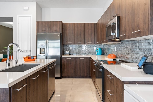 kitchen featuring sink, decorative backsplash, a kitchen island, appliances with stainless steel finishes, and light tile patterned flooring