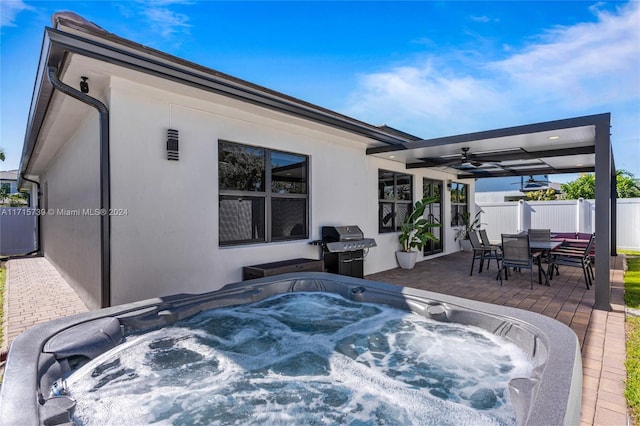 view of patio with ceiling fan, area for grilling, and a hot tub