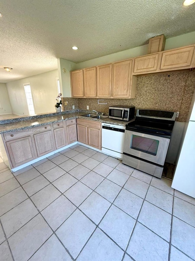 kitchen with decorative backsplash, appliances with stainless steel finishes, light brown cabinetry, a textured ceiling, and sink