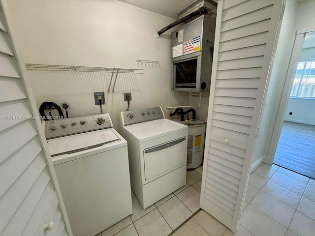 laundry area with separate washer and dryer, light tile patterned floors, and water heater