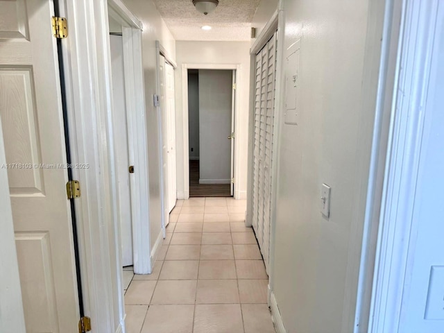 corridor with light tile patterned floors and a textured ceiling