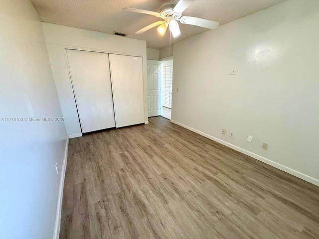 unfurnished bedroom with ceiling fan, a closet, a textured ceiling, and light wood-type flooring