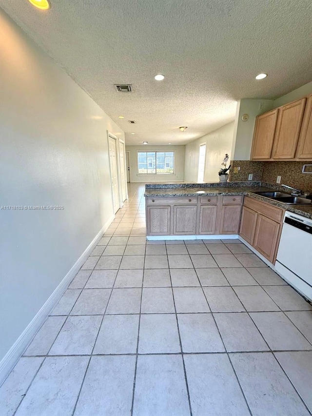 kitchen with white dishwasher, sink, light tile patterned floors, tasteful backsplash, and kitchen peninsula