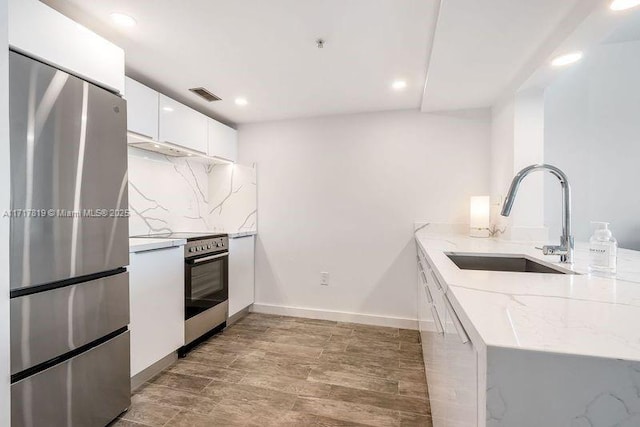 kitchen with visible vents, a sink, electric range oven, backsplash, and freestanding refrigerator