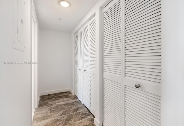 corridor with baseboards and wood finished floors