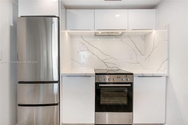 kitchen featuring white cabinetry, extractor fan, appliances with stainless steel finishes, backsplash, and light stone counters