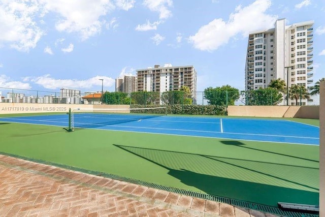 view of tennis court featuring a city view and fence