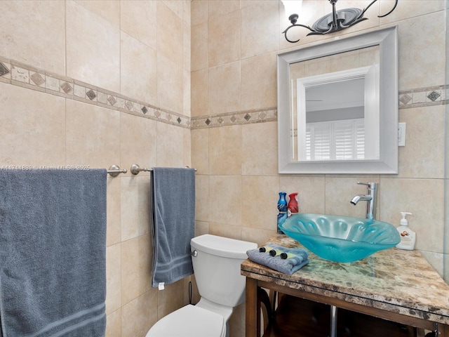 bathroom featuring vanity, toilet, and tile walls