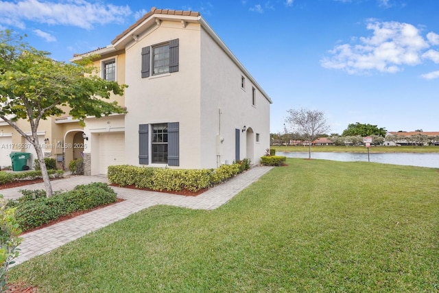 view of side of home with a lawn, a garage, and a water view