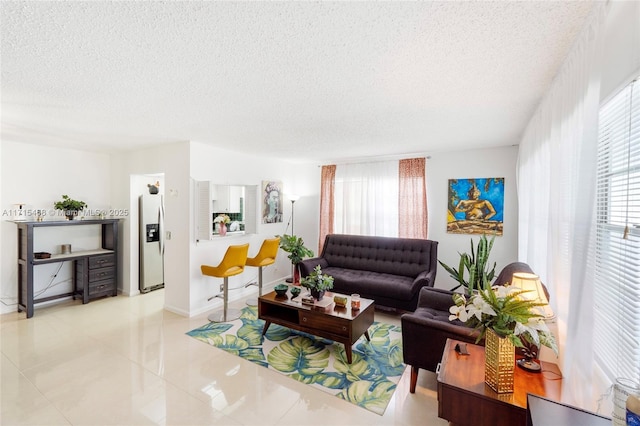 living room featuring light tile patterned flooring, a textured ceiling, and a wealth of natural light