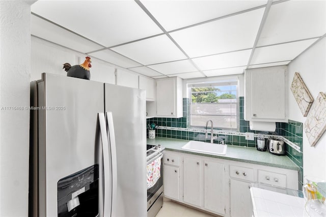 kitchen with decorative backsplash, a drop ceiling, white cabinetry, and stainless steel appliances