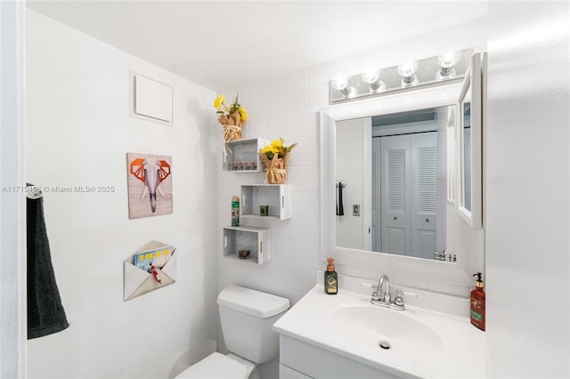 bathroom featuring vanity, tasteful backsplash, toilet, and tile walls