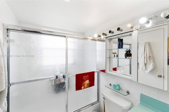 bathroom with toilet, shower / bath combination with glass door, tile walls, and tasteful backsplash