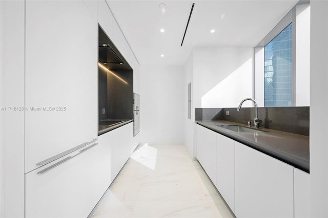 kitchen featuring white cabinets, sink, and tasteful backsplash