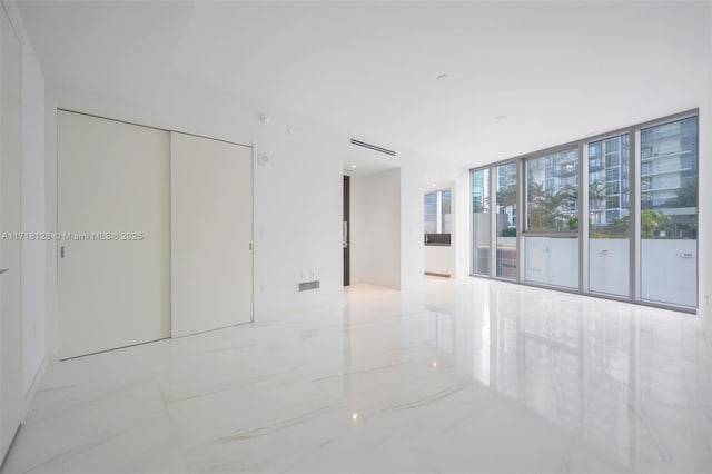 unfurnished bedroom featuring access to exterior, a wall of windows, and a closet