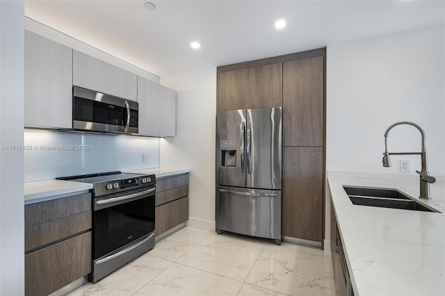 kitchen featuring sink, light stone countertops, and stainless steel appliances