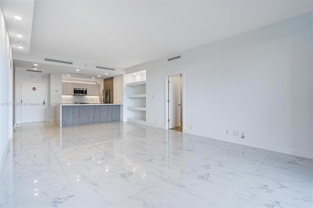 unfurnished living room with built in shelves