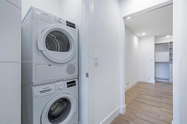 clothes washing area featuring light hardwood / wood-style flooring and stacked washing maching and dryer