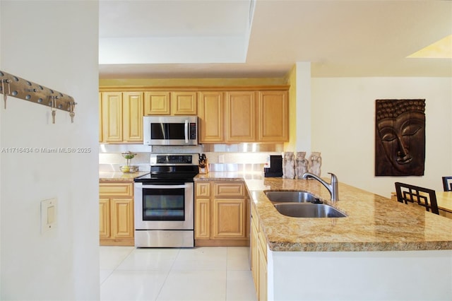 kitchen featuring light stone countertops, kitchen peninsula, sink, and appliances with stainless steel finishes