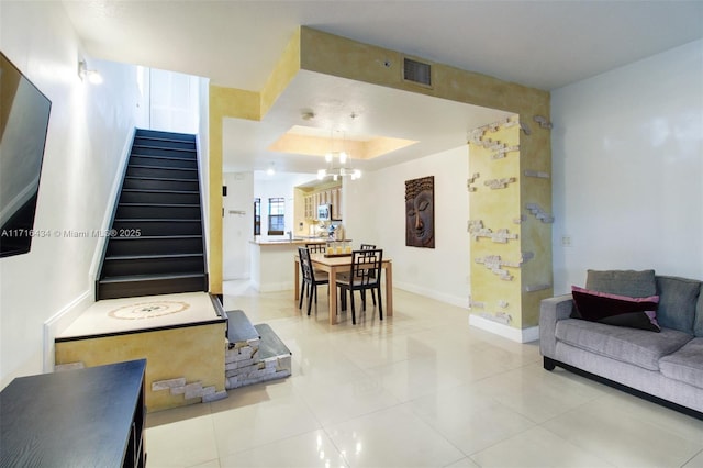 living room featuring a chandelier, a raised ceiling, and tile patterned floors