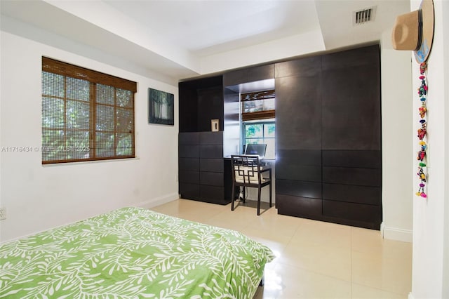 bedroom with a tray ceiling and light tile patterned flooring