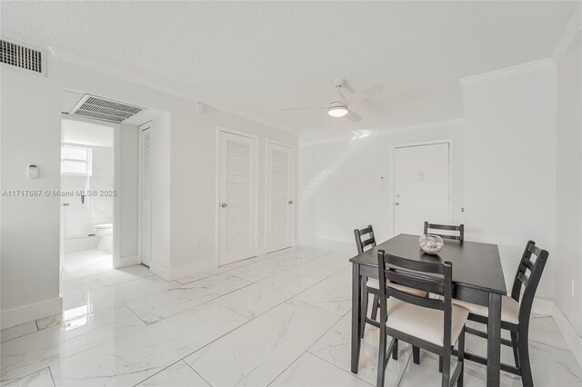 dining space with a textured ceiling, ceiling fan, and ornamental molding