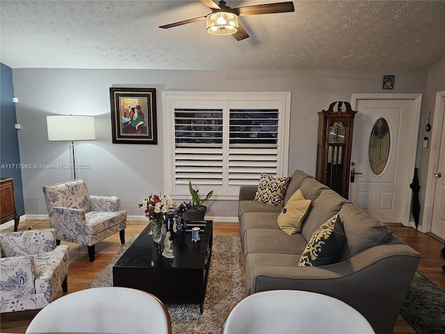 living room featuring ceiling fan, wood-type flooring, and a textured ceiling