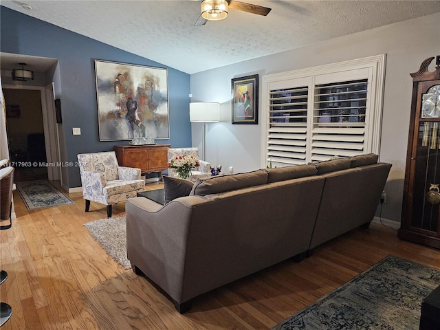 living room with a textured ceiling, light hardwood / wood-style flooring, ceiling fan, and lofted ceiling