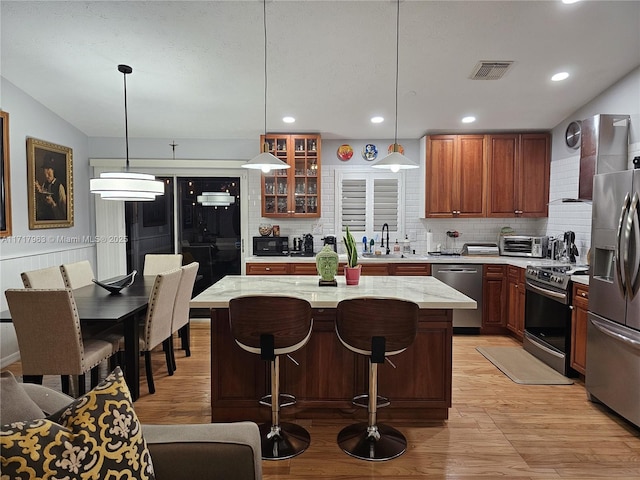 kitchen featuring sink, a center island, hanging light fixtures, tasteful backsplash, and appliances with stainless steel finishes