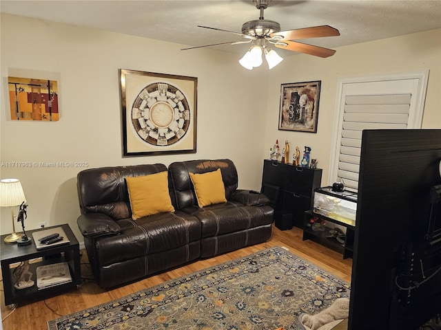 living room featuring ceiling fan, wood-type flooring, and a textured ceiling