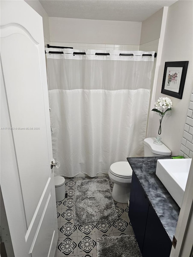 bathroom with tile patterned flooring, vanity, toilet, and a textured ceiling